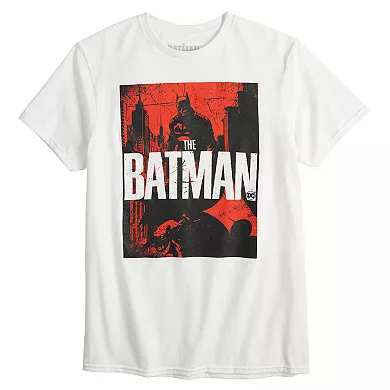 White t-shirt featuring a red and black design with \“The Batman\“ movie title and a silhouetted character in a cape standing amidst city buildings.