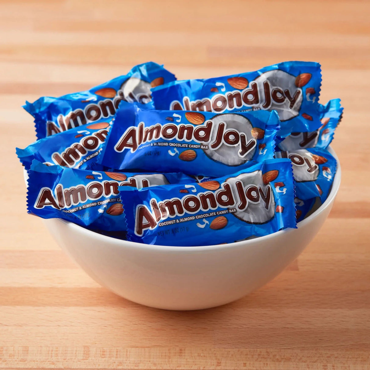 A bowl filled with individually wrapped Almond Joy candy bars, featuring a blue wrapper with images of almonds and coconuts.