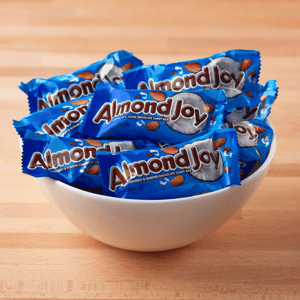 A bowl filled with individually wrapped Almond Joy candy bars, featuring a blue wrapper with images of almonds and coconuts.