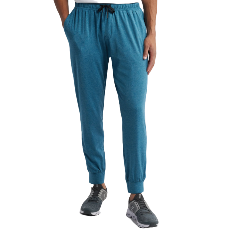 Blue joggers with an elastic waistband, black drawstring, and cuffed ankles. Made from a soft, breathable material for comfort and mobility, paired with gray athletic sneakers.