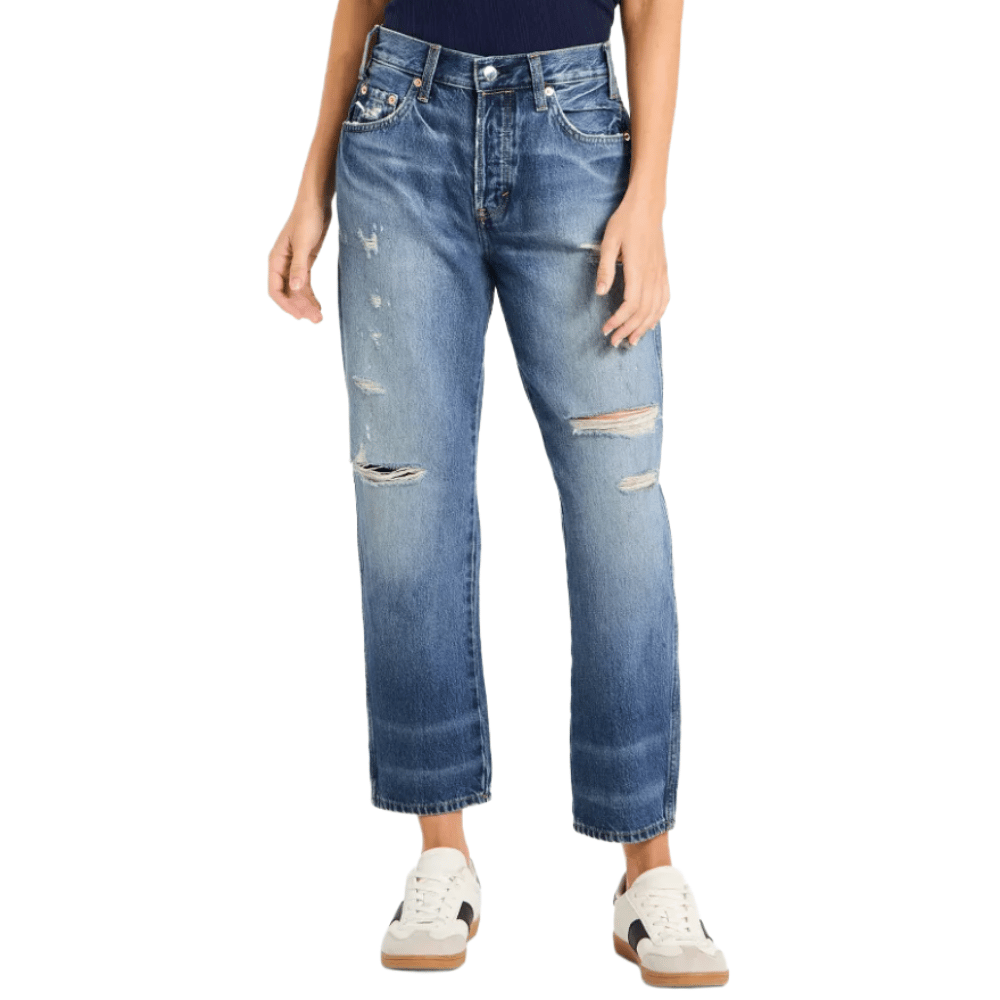 A person is wearing high-waisted, distressed blue jeans with frayed hems and white sneakers featuring a black accent.