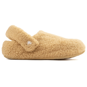 A beige, fluffy slipper with a strap is pictured, adorned with a small circular emblem on the side.