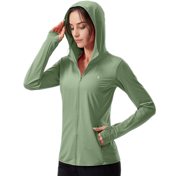 A woman is wearing a light green, long-sleeve athletic zip-up jacket with a hood and thumbholes, suitable for outdoor activities.