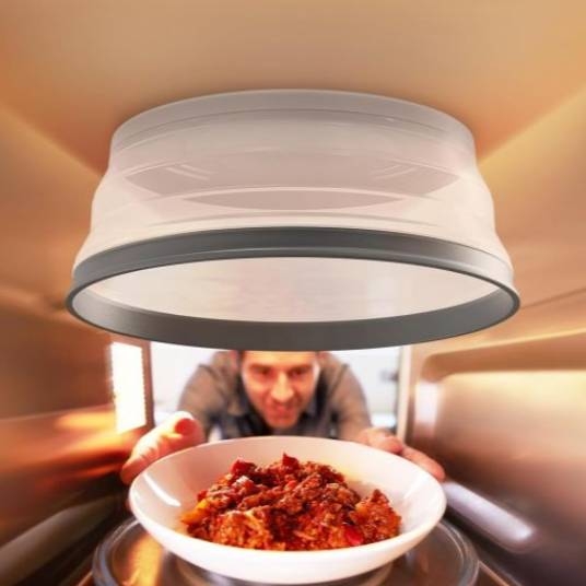 A person is putting a bowl of food into a microwave, as viewed from inside the microwave.