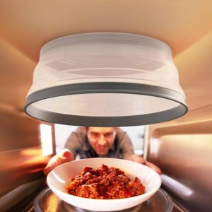 A person is putting a bowl of food into a microwave, as viewed from inside the microwave.