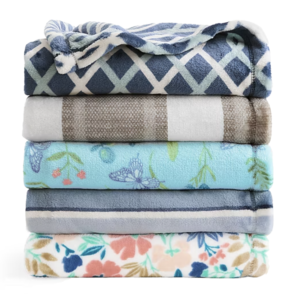 A stack of five folded blankets with various patterns: blue and white diamond, plaid, blue with butterflies, striped blue, and floral.