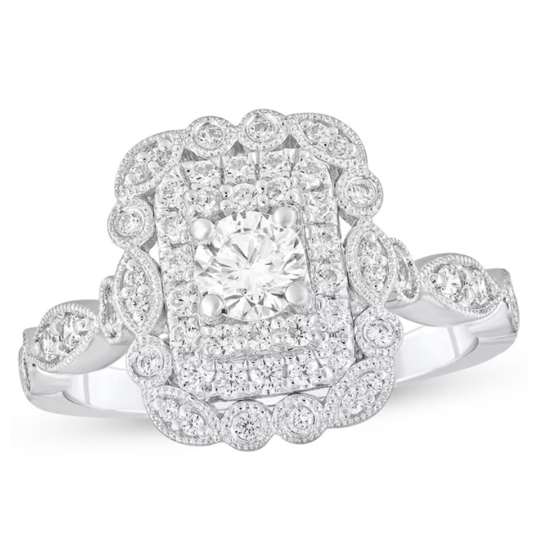 Ornate white gold ring with a central round diamond surrounded by a rectangular cluster of smaller diamonds and intricate milgrain detailing.
