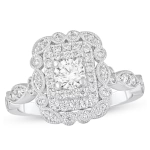 Ornate white gold ring with a central round diamond surrounded by a rectangular cluster of smaller diamonds and intricate milgrain detailing.