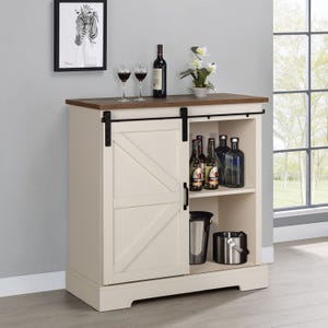 A beige kitchen cabinet with a sliding door, wooden countertop, wine glasses, bottles, and metallic bins.
