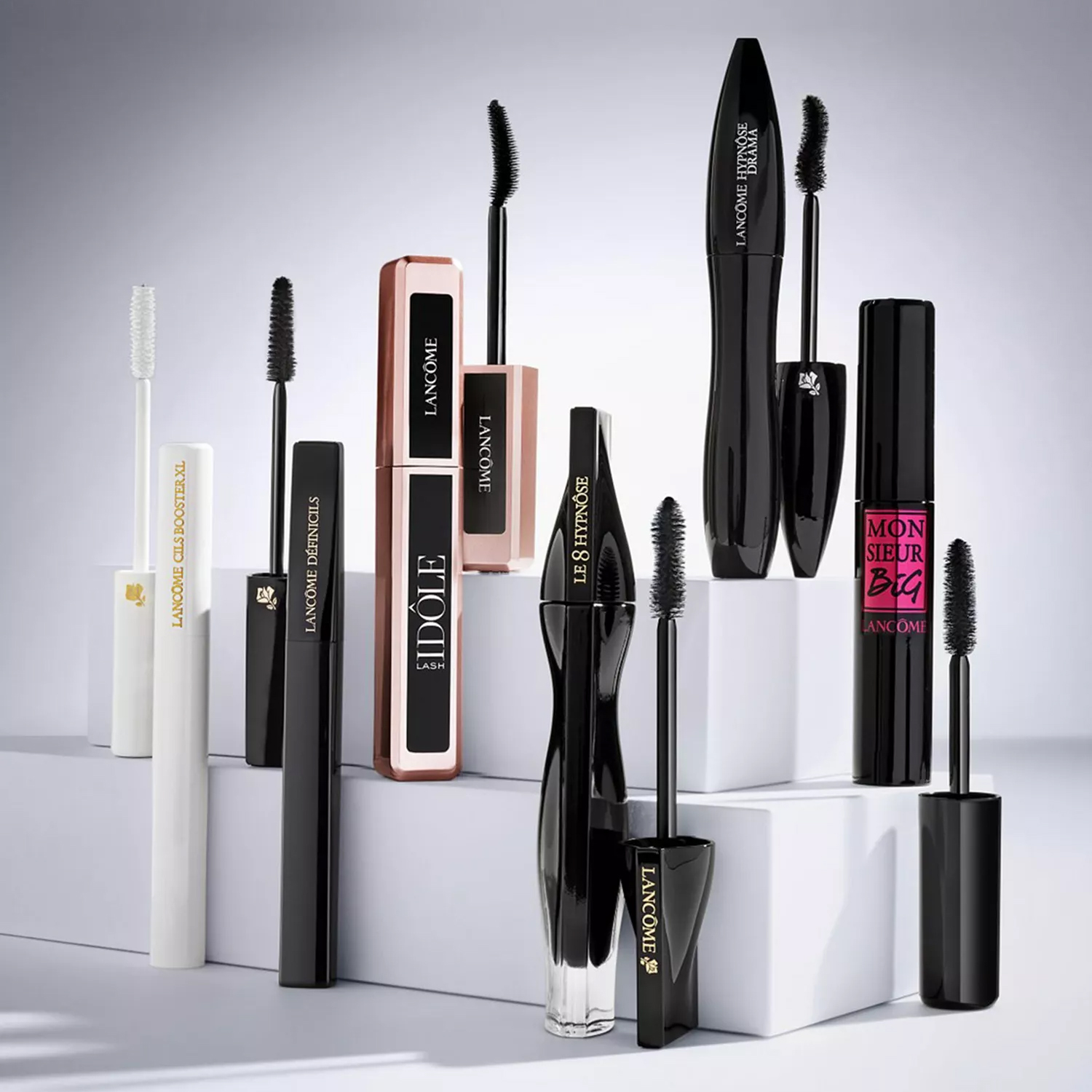A collection of Lancôme mascaras is displayed, featuring various designs, including Idôle Lash, Le 8 Hypnôse, and Monsieur Big, alongside a white lash primer.