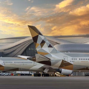 Etihad Airways airplane with a geometric-patterned tail design is parked at an airport terminal during sunset, showcasing its branding and livery.