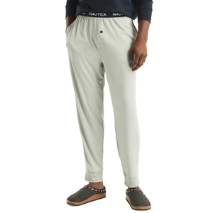 Men's pale gray pajama pants with an elastic waistband featuring the \“Nautica\“ logo and a button fly, paired with gray wool slippers with multicolored strap detailing.