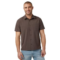 A casual short sleeve dress shirt in dark brown features a button-down front, a classic collar, and a chest pocket. It's paired with light blue jeans.