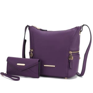 A purple MKF shoulder bag with gold-tone zippers and an adjustable strap, paired with a matching envelope-style wallet featuring a wrist strap. Both items have gold-tone brand logos.