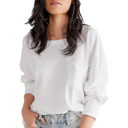 A woman wearing a white long-sleeve blouse with a chest pocket, paired with denim jeans.