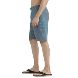Man wearing blue board shorts with \“Salt Life\“ text on the side in light blue, paired with black flip-flops.