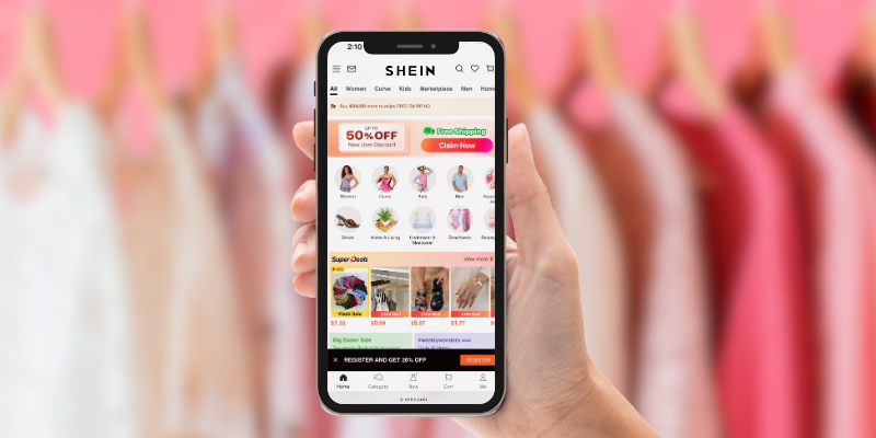 person holding iphone in front of clothing rack