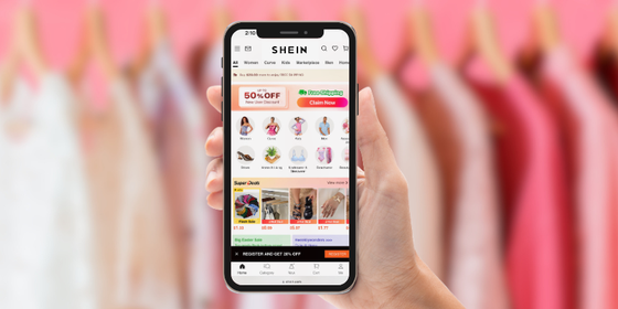 person holding iphone in front of clothing rack