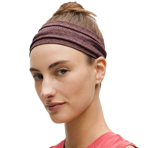 A woman with a brown headband styled in a layered design and wearing a red sleeveless top.