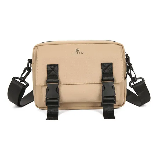 A beige crossbody bag with black adjustable straps and dual front buckle closures, featuring the brand name \“LIOR\“ on the front.