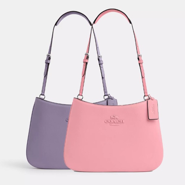 Two leather shoulder bags in pastel purple and pink with adjustable straps and brand logo.