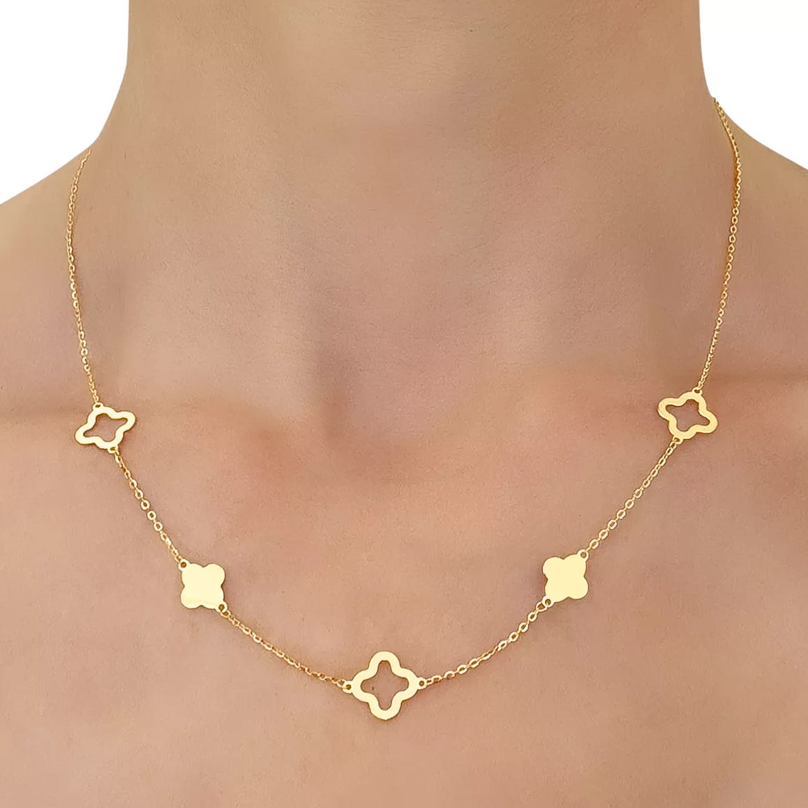 Gold necklace featuring a delicate chain with alternating solid and open quatrefoil motifs.