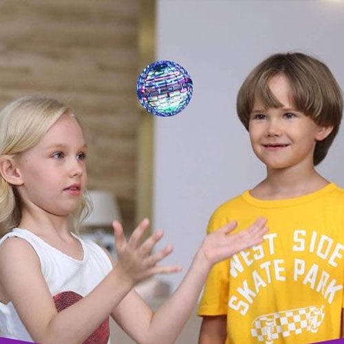 Two children are playing with a colorful, hovering ball, likely a flying spinner toy. The boy is wearing a yellow \“West Side Skate Park\“ shirt.