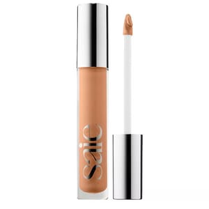 A concealer with a doe-foot applicator featuring a sleek silver cap and a clear tube displaying the brand name \“Saie.\“