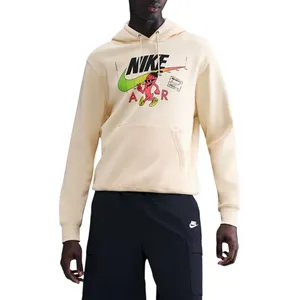Model in a Nike outfit featuring a cream hoodie with graphic print, black shorts with a Nike logo, black socks, white sneakers, and a black cap.