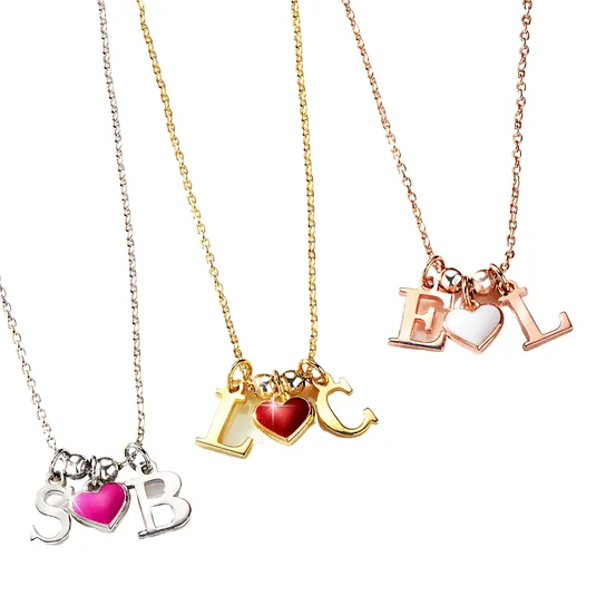 Three necklaces feature gold, silver, and rose gold chains, each with two letters and a colored heart charm: pink with \“S\“ and \“B,\“ red with \“L\“ and \“C,\“ and white with \“E\“ and \“L.\“