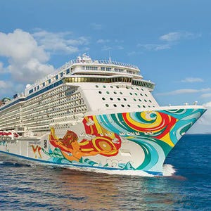 A large cruise ship decorated with vibrant, colorful artwork on its hull sails through clear blue water.