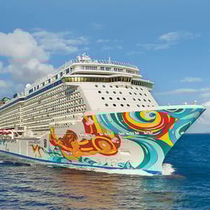 A large cruise ship decorated with vibrant, colorful artwork on its hull sails through clear blue water.