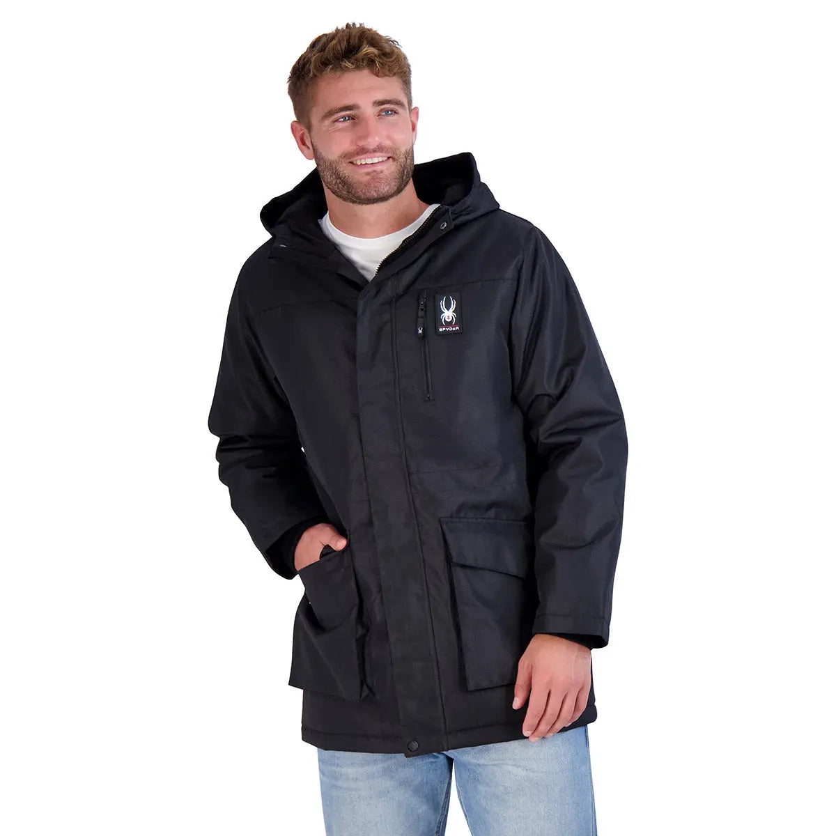 A man is wearing a black Spyder parka with a hood, featuring a logo on the chest and two large front pockets.