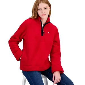 A person is wearing a red fleece pullover with a half-zip and small logo on the chest, paired with blue jeans.
