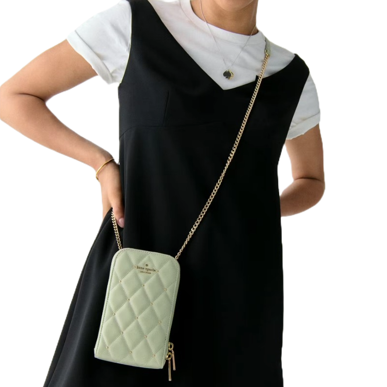 A person wears a white shirt under a black dress, accessorized with a quilted mint green crossbody bag featuring a gold chain strap.