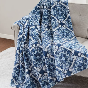 A blue and white floral patterned quilt is draped over a beige armchair.