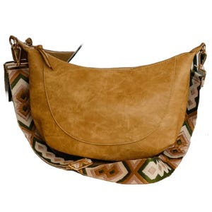 Tan leather shoulder bag with a geometric patterned strap in earthy tones of green and brown.