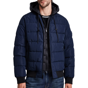 A navy blue quilted hooded jacket with black drawstrings and a front zipper, paired with blue jeans.