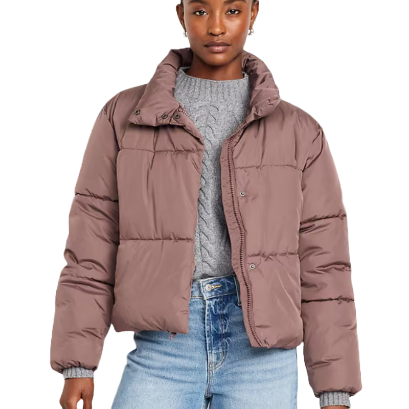 A woman is wearing a quilted puffer jacket in a muted rose color with a zip front, side pockets, and a stand-up collar.