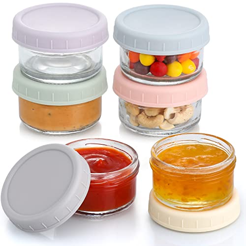 Six round glass jars with colorful screw-on lids, filled with various condiments and snacks, arranged in a staggered formation.