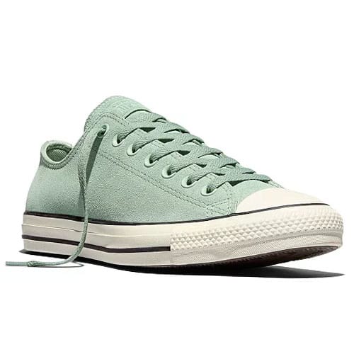 A light green low-top sneaker with white rubber toe cap and soles, featuring a lace-up design and black stripe detailing.