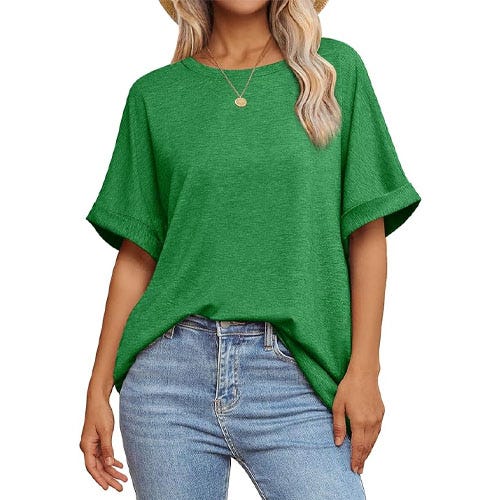 A woman wearing a solid green t-shirt tucked into light colored blue jeans.