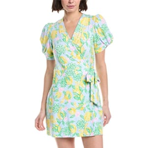 A woman wears a short, floral wrap dress with puffy short sleeves and a V-neck, featuring a pastel-colored pattern with green leaves and yellow flowers.