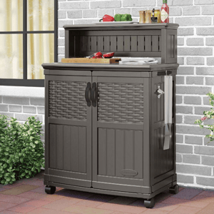 Outdoor storage cabinet with wheels, featuring two doors and a towel holder, topped with kitchen items like a cutting board and condiments.