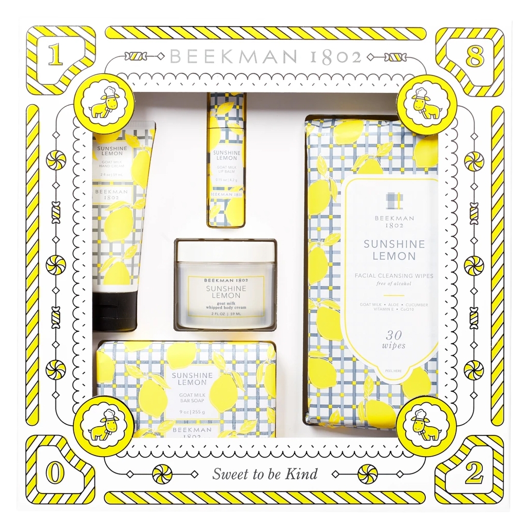 Beekman 1802 Sunshine Lemon Skincare Set includes bar soap, whipped body cream, hand cream, facial cleansing wipes, and lip balm, all featuring goat milk and zesty lemon fragrance, presented in a decorative, lemon-patterned box.