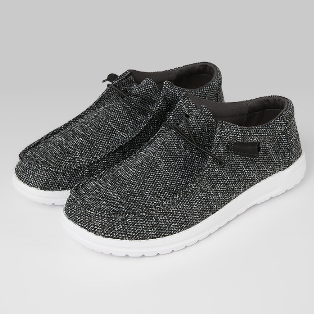 A pair of textured black and white sneakers with laces and a white sole.