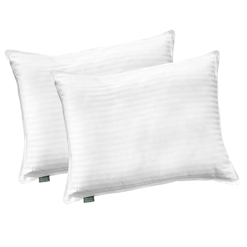 Two white pillows with a subtle striped pattern, labeled with a small green tag.