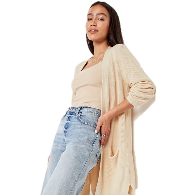 A woman is wearing light blue jeans, a beige top, and a cream longline cardigan.