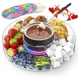 A fondue set featuring a central pot with melted chocolate surrounded by strawberries, blueberries, kiwi, cookies, pistachios, marshmallows, and tacos on a transparent tray with festive decorations. A set of colorful game spinners is included.