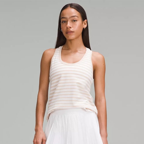 A woman wears a sleeveless, scoop-neck tank top with thin horizontal stripes, paired with a white skirt.